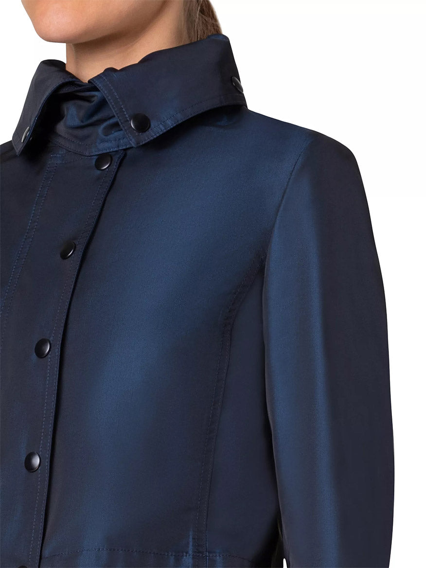 Close-up of a person wearing an Akris Punto Techno Water Resistant Satin Short Jacket in Ink crafted from water-repellent techno satin with a high snap-button collar.