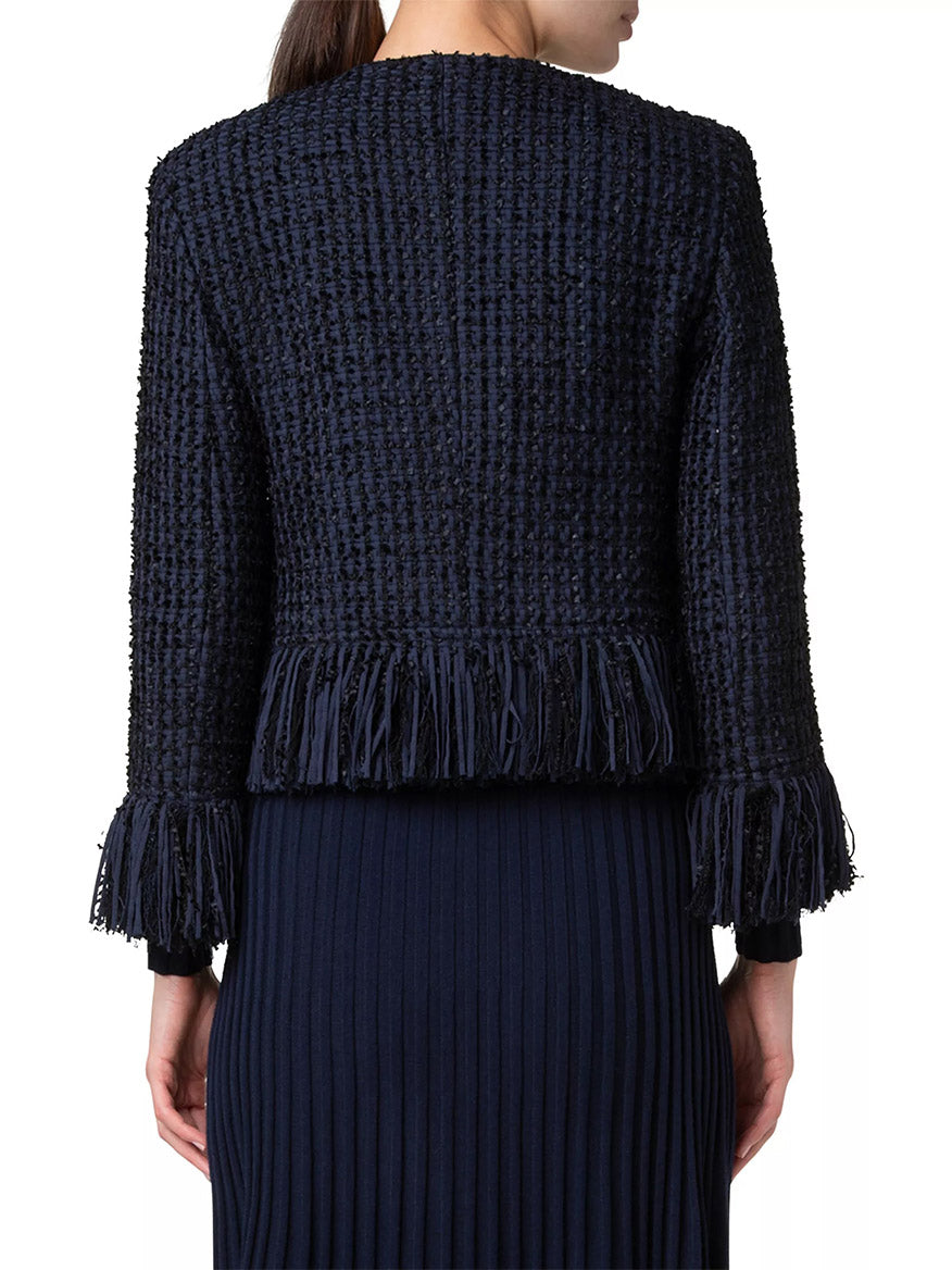 Back view of a person wearing a navy Akris Punto Chunky Tweed Cropped Jacket with fringe detailing on the sleeves and hem, paired with a matching ribbed dress.