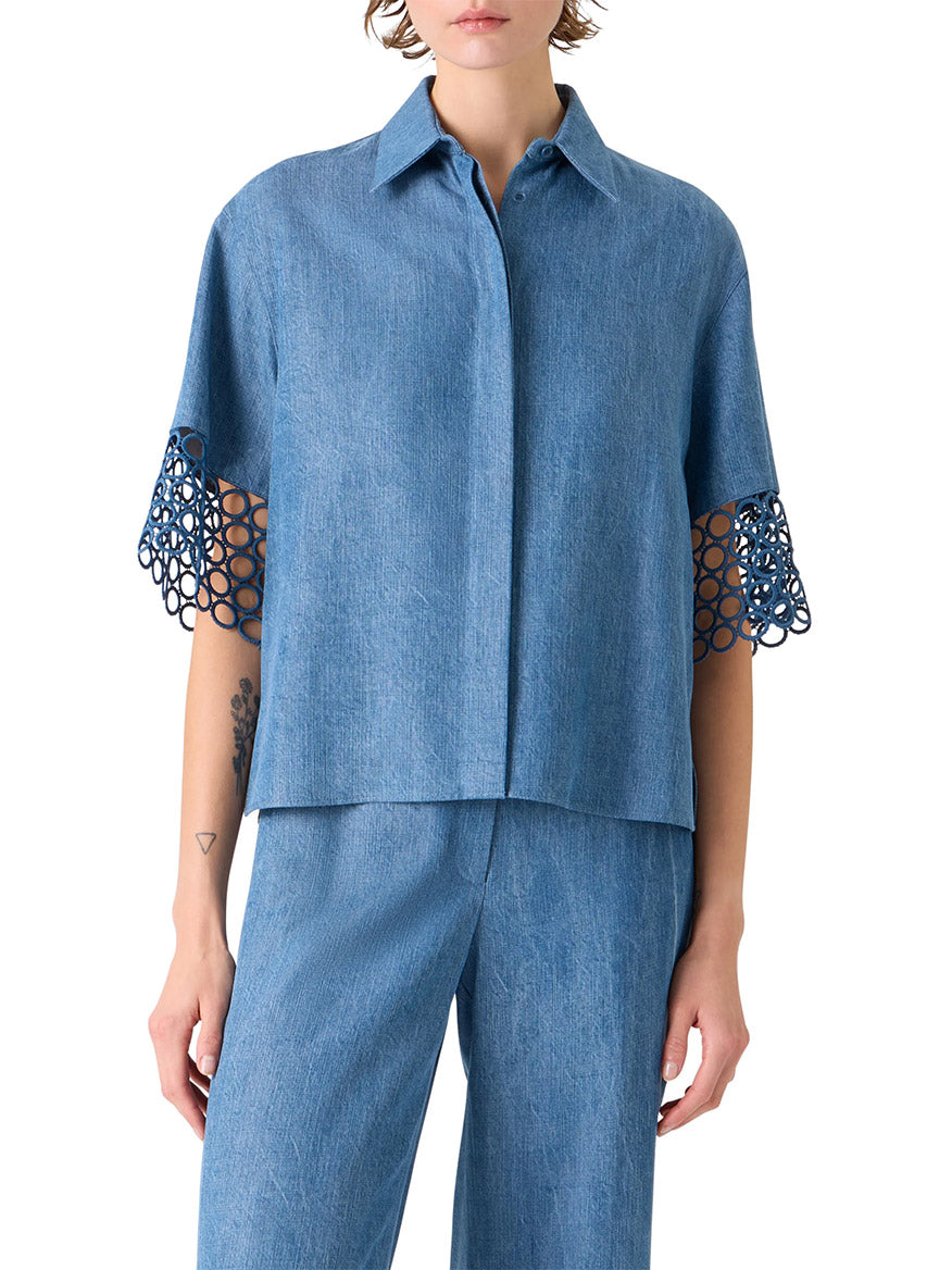 Someone wearing the Akris Punto Washed Denim Circle Lace Shirt in Medium Blue, featuring a boxy fit and open-circle lace trim on the elbow-length sleeves, styled with coordinating blue pants.