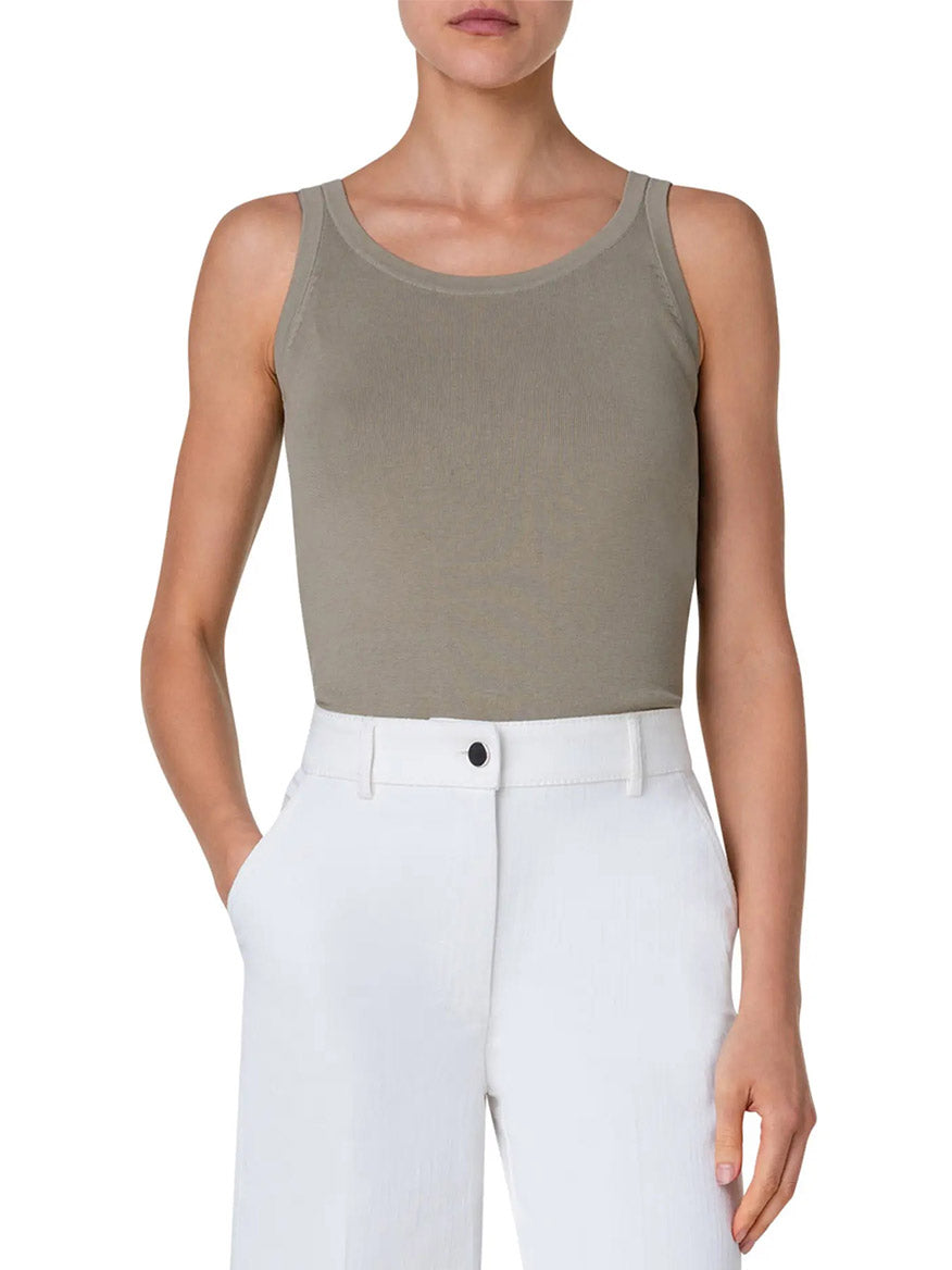 A woman wearing a sleeveless Akris Punto scoop neck cotton tank top in sage pairs it elegantly with white pants.