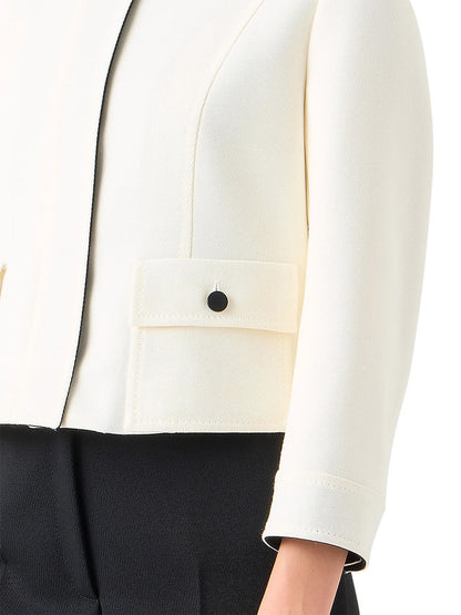A person wearing an Akris Punto Wool Tricotine Stand Collar Jacket in Cream/Black, paired with black pants.
