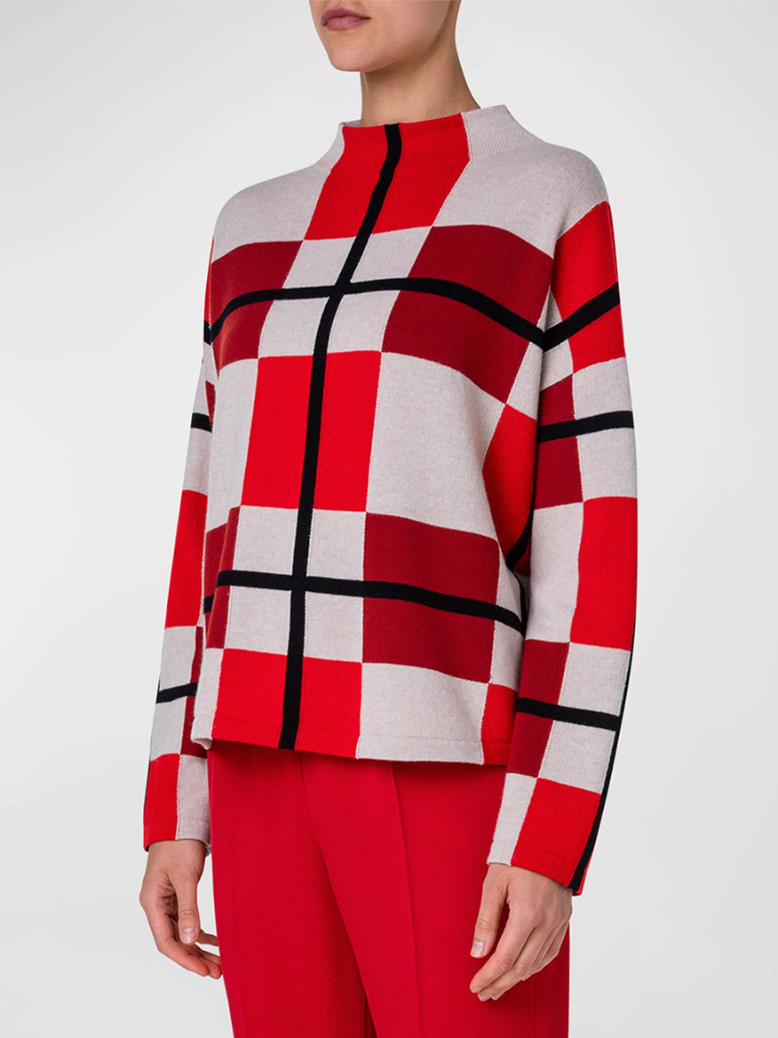 A woman wearing a red and black checkered Akris Punto XL Cube Check Funnel Neck Sweater in Red Multi.