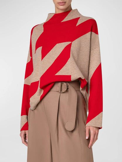 A person is wearing an Akris Punto XL Houndstooth Wool/Cashmere Mockneck in Lipstick/Caramel and high-waisted beige trousers with a belt, showcasing a modern boxy fit.