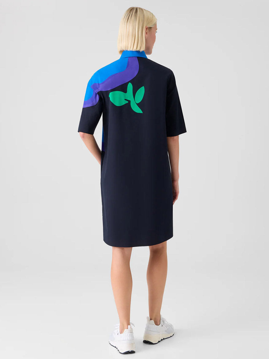 A person with short blonde hair wears the Akris Punto XL Pop Dot Flower Cotton Dress in Black Multi, paired with white sneakers.