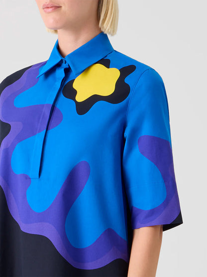 A person wearing the Akris Punto XL Pop Dot Flower Cotton Dress in Black Multi, featuring a blue, purple, and black abstract floral print with a bold yellow accent near the shoulder.