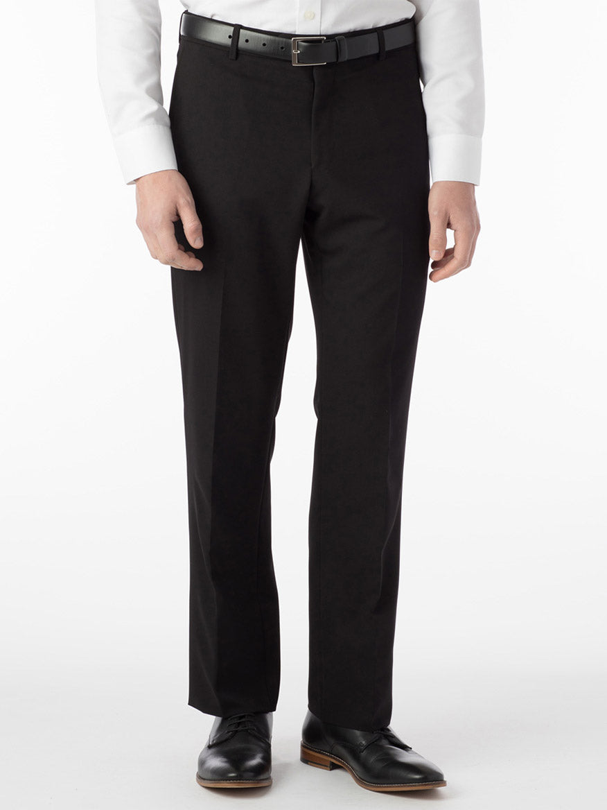 A person wearing Ballin Soho Comfort 'EZE' Commuter Bi-Stretch Gabardine Modern Flat Front Pants in black, a white long-sleeve shirt, black belt, and black dress shoes stands against a plain white background.