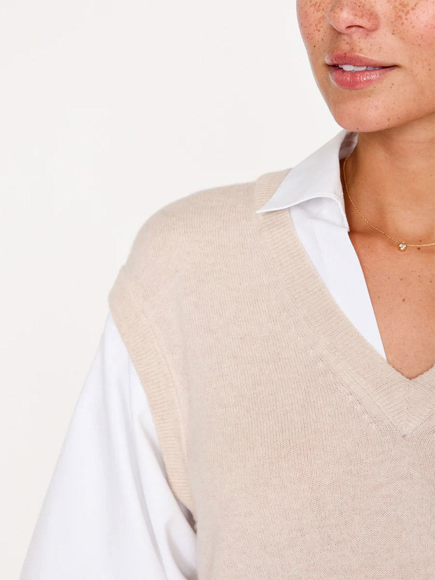 A close-up of a woman's neck and shoulder area, showcasing her wearing an Almond Buff Melange Brochu Walker Kate Shirt Looker over a white collared shirt, with a delicate gold necklace and dramatic blouson sleeves.