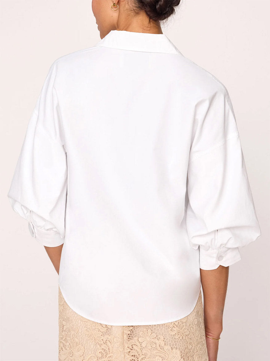 A woman seen from behind wearing a white Brochu Walker Kate Shirt in Salt White with button cuff sleeves, exuding effortless sensuality.