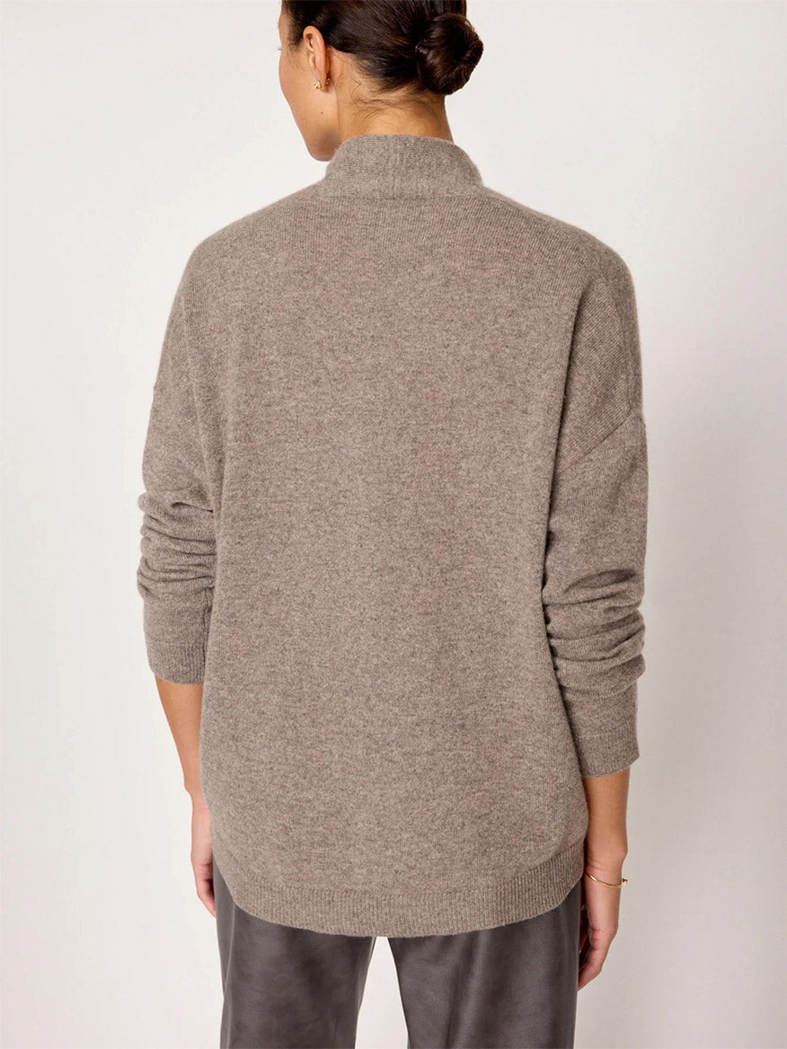 A person with their hair in a bun is seen from behind, wearing the Brochu Walker Siena Wrap Neck Pullover in Otter Melange and gray pants, exuding an air of luxe femininity.