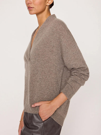 A person wearing the Brochu Walker Siena Wrap Neck Pullover in Otter Melange, standing in profile with one hand in their pocket, exuding luxe femininity.