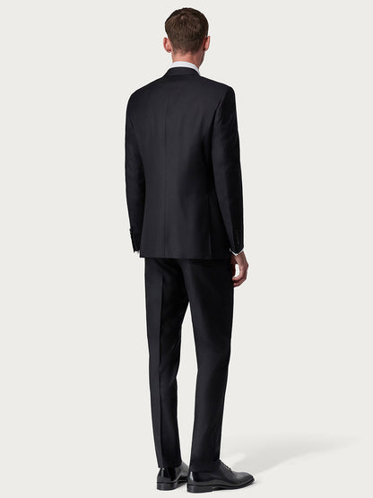 Man in a Canali Siena Contemporary Black Wool Suit standing with his back to the camera, on a plain background. He’s also wearing black shoes.