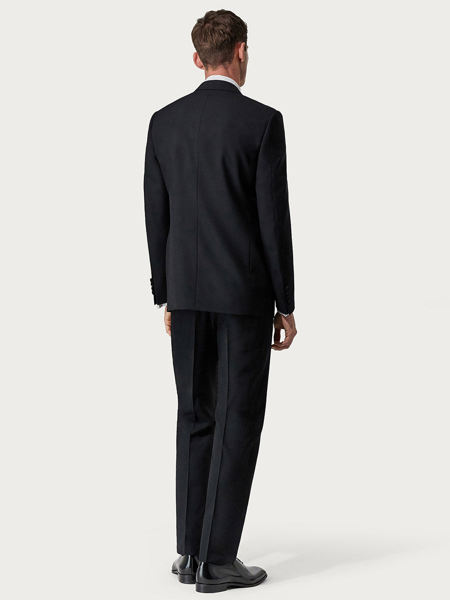 Rear view of a man wearing a Canali Siena Black Wool Tuxedo with Peak Lapels, standing against a light background.