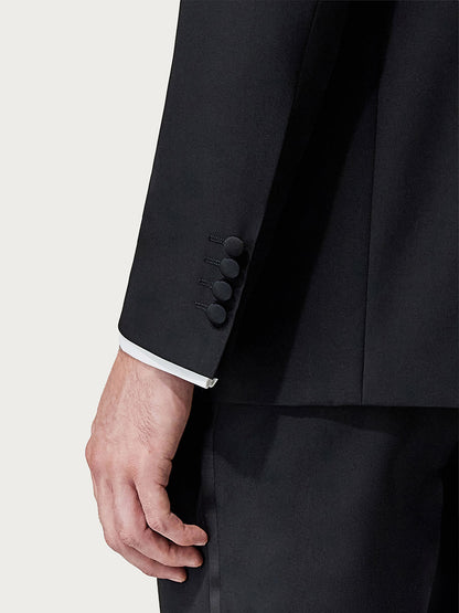 Close-up of a man's arm in a Canali Siena Black Wool Tuxedo With Peak Lapels with focus on the cuff showing detail of white shirt cuff and suit sleeve buttons.