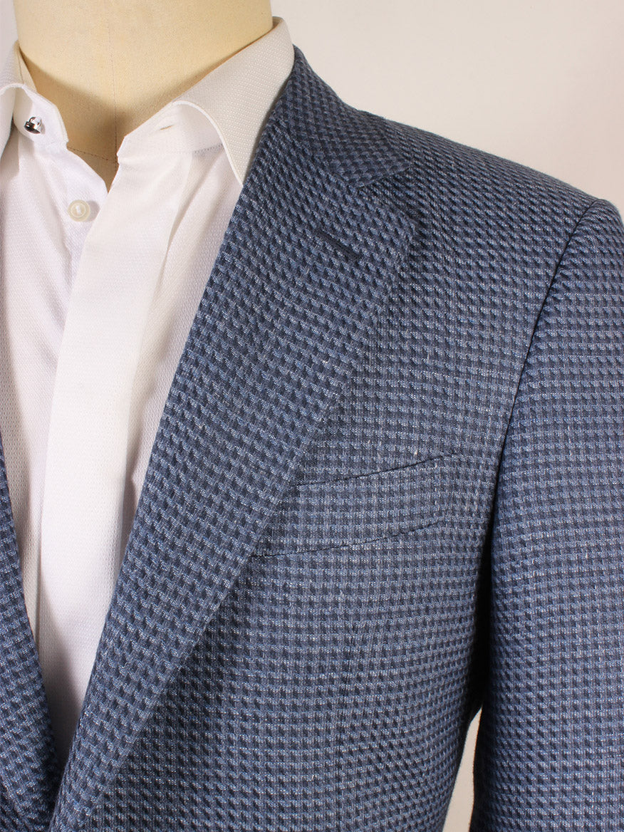 Close-up of a person wearing the Canali Flap Pocket Sport Jacket in Mid Blue, crafted in Italy from a linen blend with a subtle check pattern, paired with a white dress shirt.