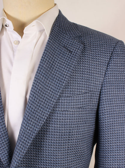 Close-up of a person wearing the Canali Flap Pocket Sport Jacket in Mid Blue, crafted in Italy from a linen blend with a subtle check pattern, paired with a white dress shirt.