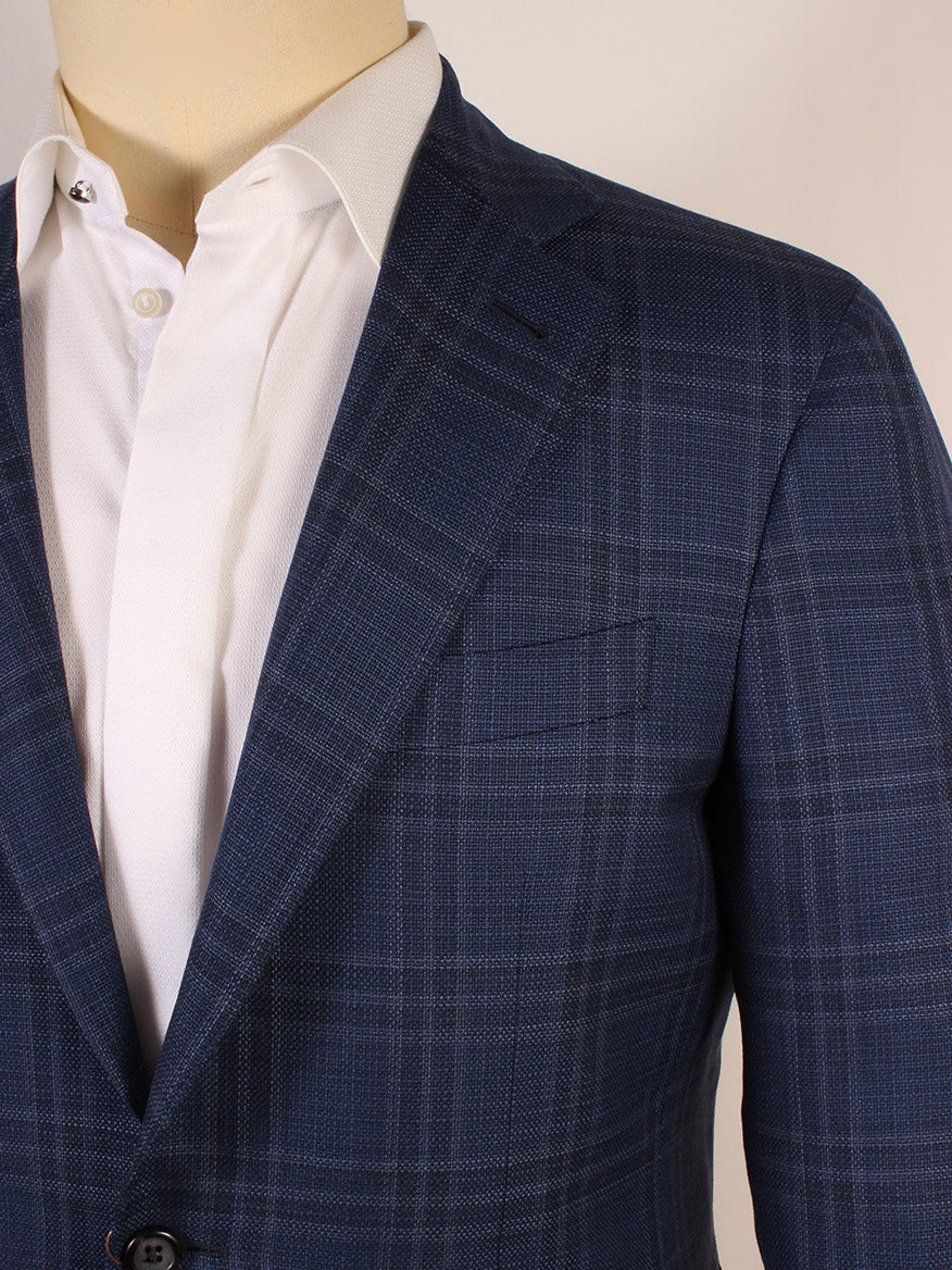 A close-up of a person wearing the Canali Kei Flap Pocket Sport Jacket in Navy Windowpane over a white dress shirt with the top button undone.