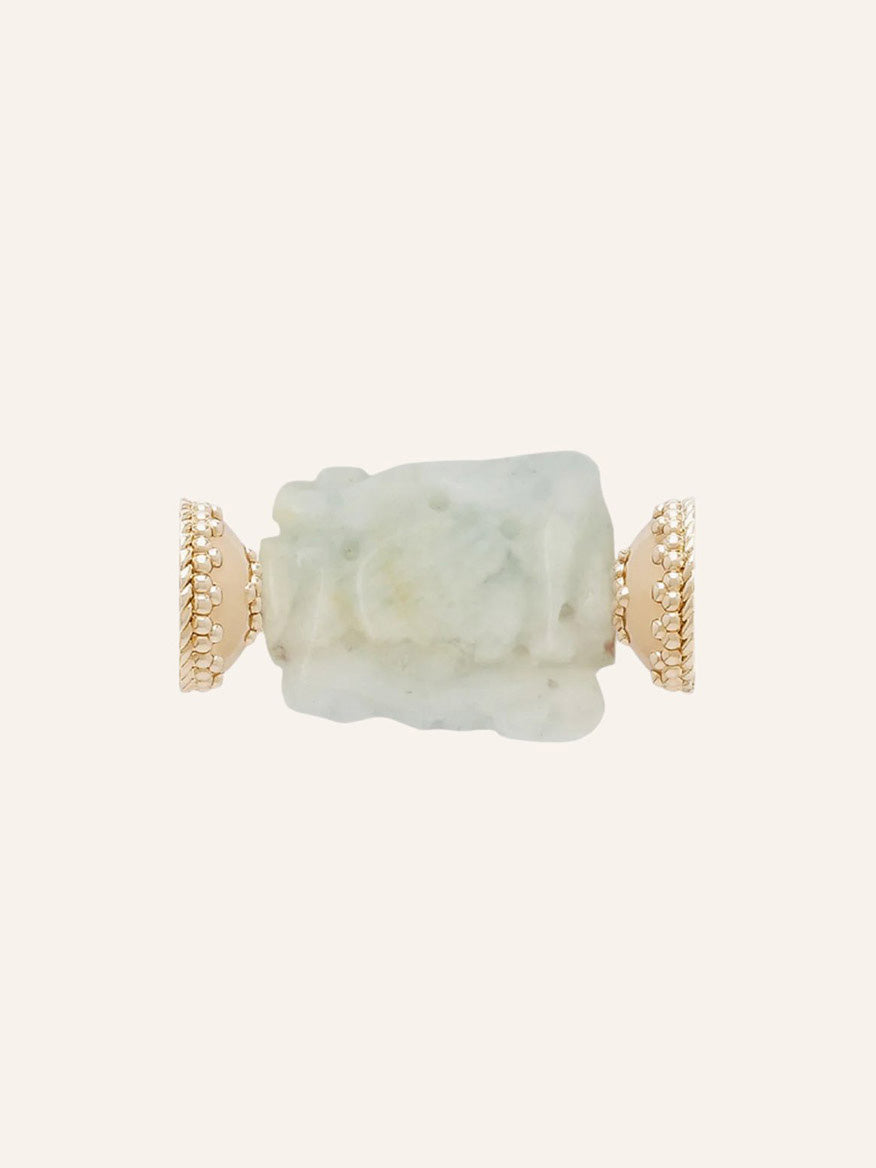 The Clara Williams Aquamarine Shield Carved Centerpiece is shown on a plain beige background, featuring a carved light green aquamarine stone held by textured 14K yellow gold prongs.