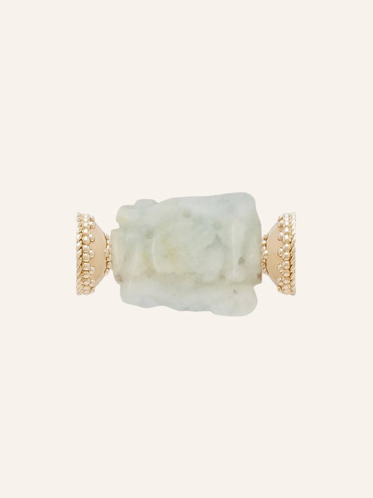 The Clara Williams Aquamarine Shield Carved Centerpiece is shown on a plain beige background, featuring a carved light green aquamarine stone held by textured 14K yellow gold prongs.
