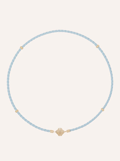 The Clara Williams Aspen Braided Light Blue Leather Mini Necklace features gold-tone bead accents and a central 14K yellow gold decorative bead, shown on a plain background.