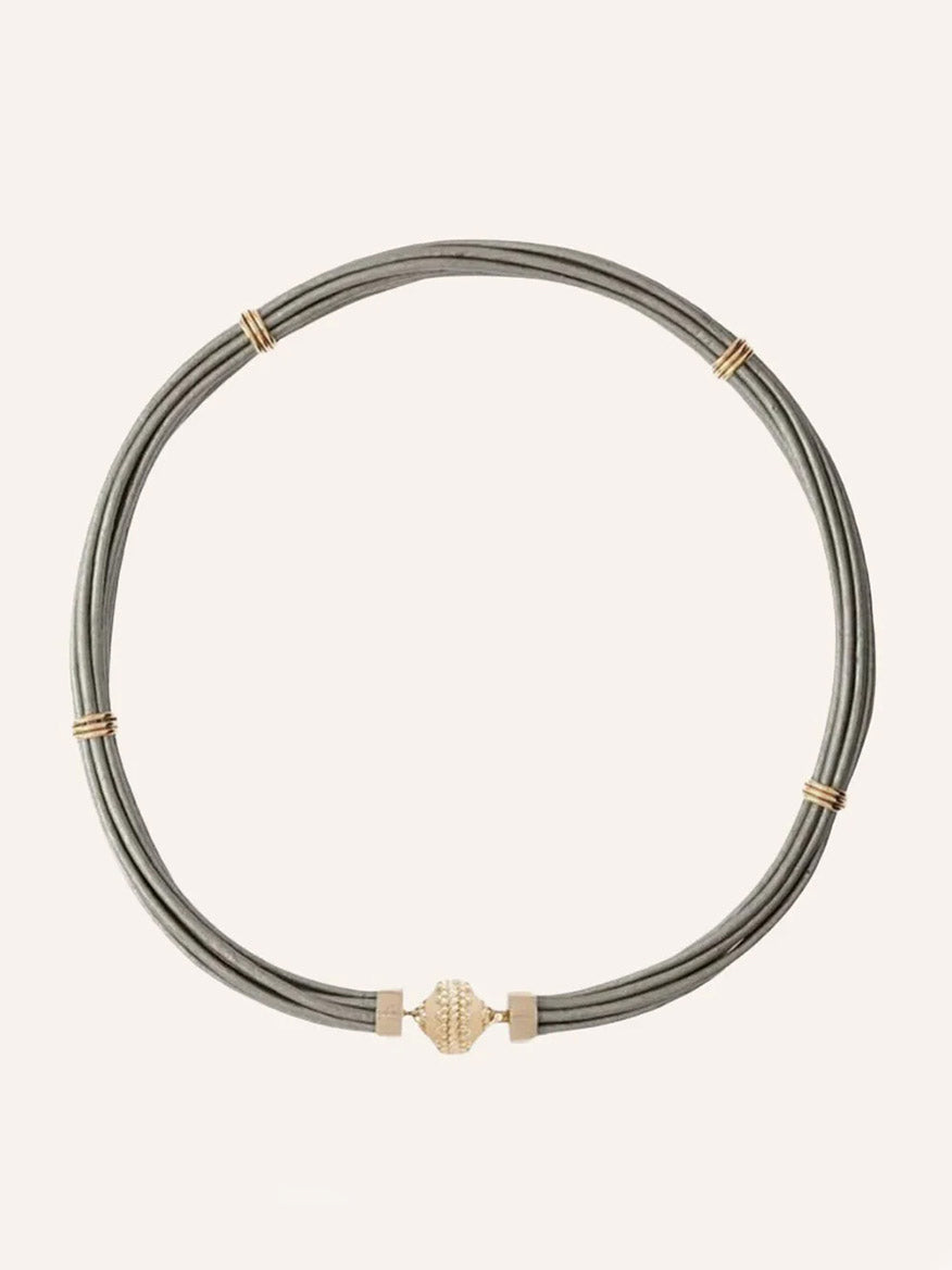 The Clara Williams Aspen Leather Platinum Silver Necklace features multiple thin gray leather cords, several platinum silver bands, and a central silver clasp.