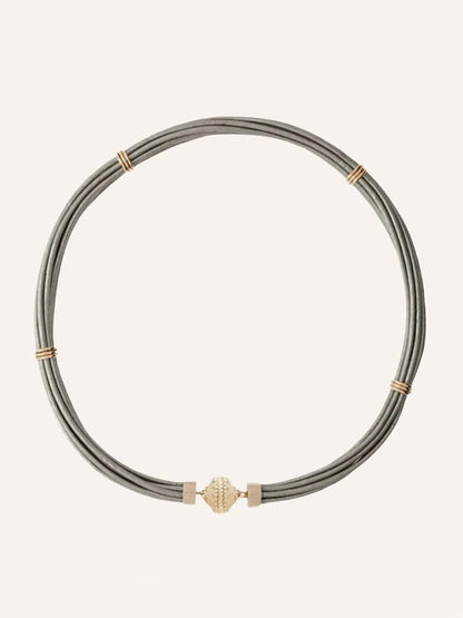 The Clara Williams Aspen Leather Platinum Silver Necklace features multiple thin gray leather cords, several platinum silver bands, and a central silver clasp.