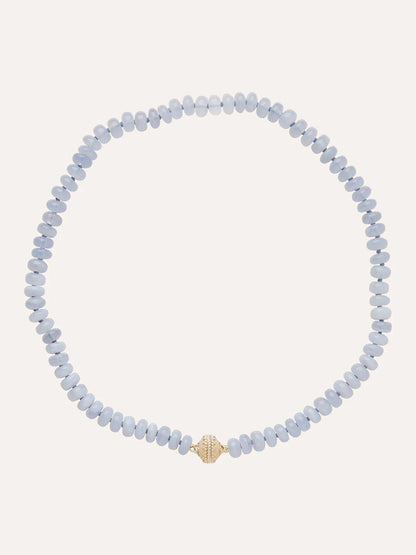 The Clara Williams Chalcedony Rondelle Mini Necklace showcases light blue Blue Chalcedony rondelle stones with a single textured 14K yellow gold bead at the center, displayed on a plain background.