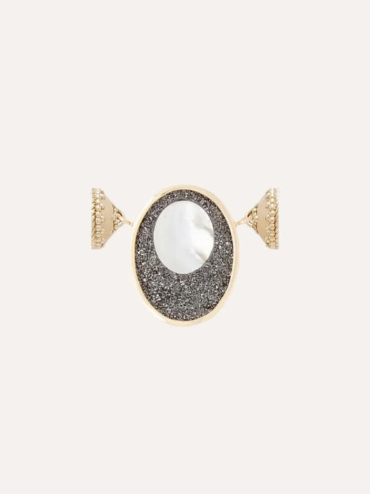 The Clara Williams 14K Black Druzy Oval Cut-Out Mini Centerpiece features an oval face with a white circular center set on a textured black druzy background, all elegantly crafted in 14K yellow gold.