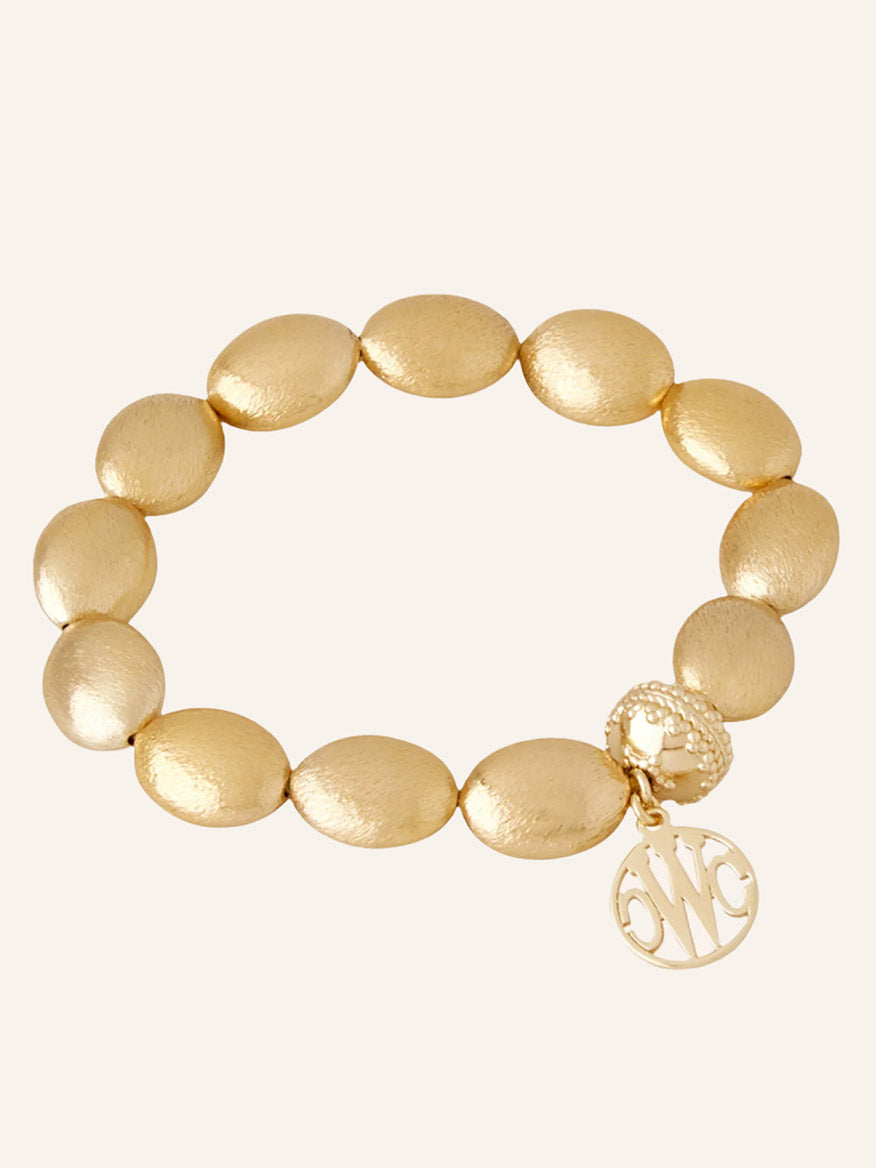 Clara Williams Gold Rush Stretch Bracelet, crafted in 14K yellow gold with a round monogrammed charm and signature textured ClaraClasp, elegantly displayed on a plain, light background.