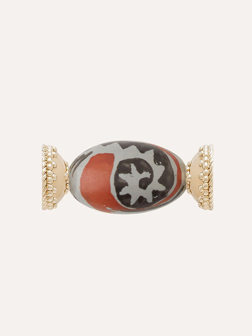 Introducing the Clara Williams Rust Horizon Ceramic Centerpiece: a bead-shaped charm with gold-toned, textured ends and a central oval featuring a striking red and black pattern with white-gray accents. This piece is crafted to pair seamlessly with a Clara Williams ceramic clasp or your favorite 14K yellow gold accessories.