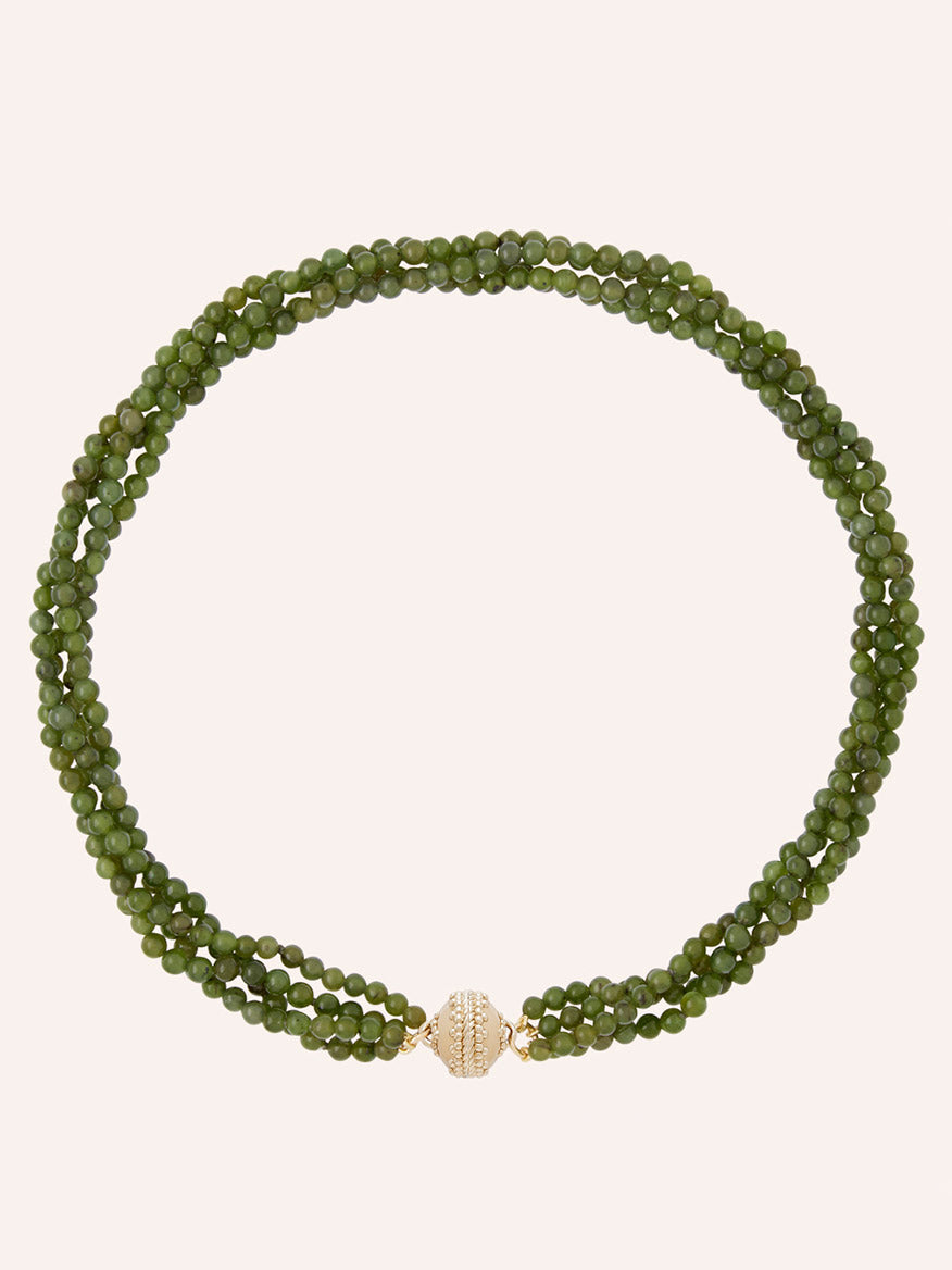 The Clara Williams Victoire 4mm Green Jade Multi-Strand Necklace, featuring three strands of green jade beads and a round 14K gold clasp adorned with small clear stones, is displayed on a plain background.