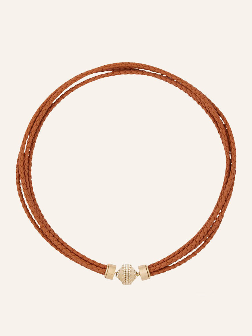 The Clara Williams Wellington Braided Leather Saddle Necklace features a double-wrap design in Saddle Brown braided leather with a 14K yellow gold cylindrical clasp, shown against a plain light background.