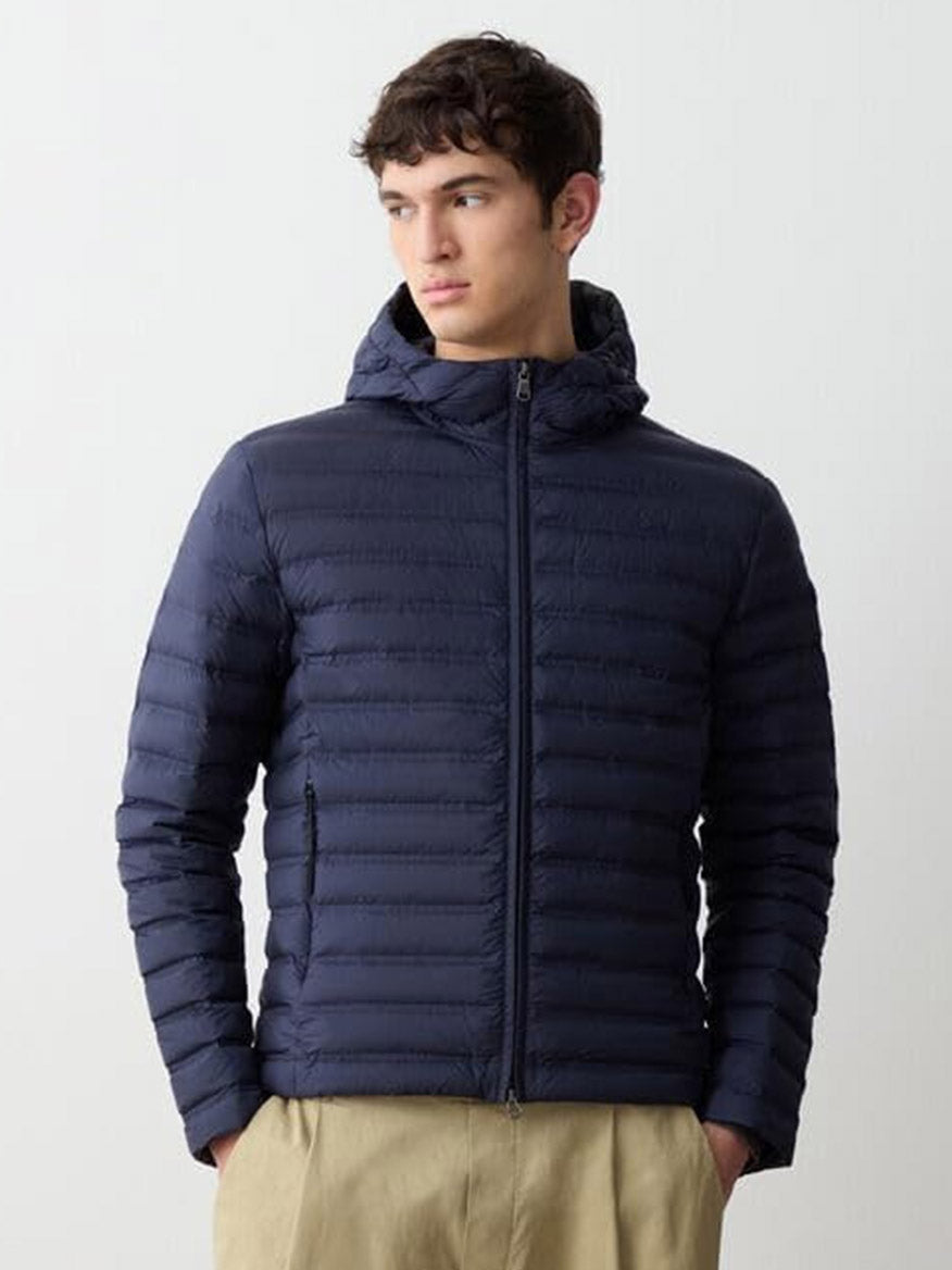 A person wears the Colmar Underscore Down Hooded Zip Jacket in Navy Blue/Vulcan with beige pants, standing slightly turned against a plain background.