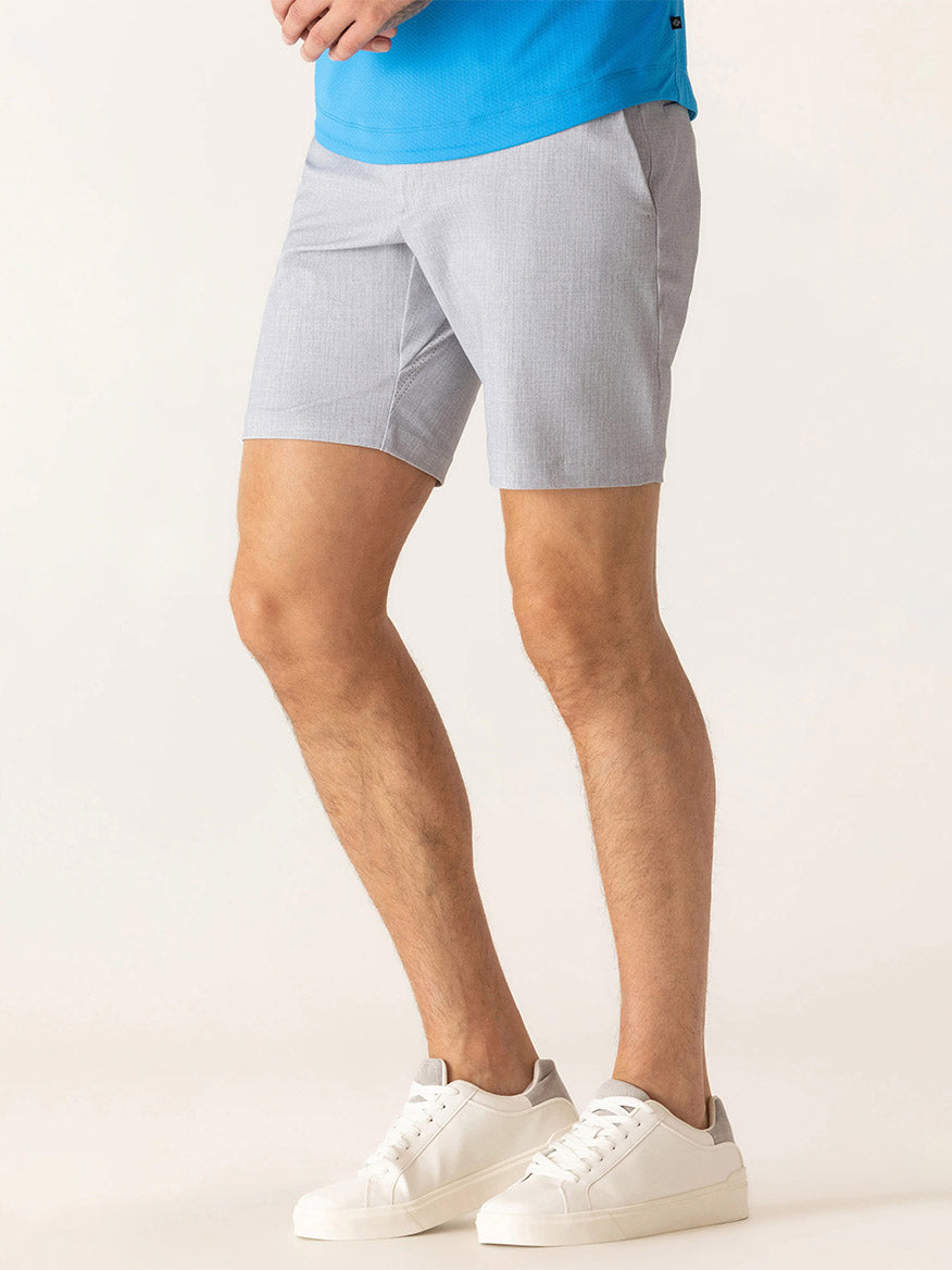 Wearing a blue Nano Nylon Warp Knit shirt, DEKE Galaxy Bermuda Nano Nylon Warp Knit shorts in Silver, and white sneakers, a person stands against a plain light background.