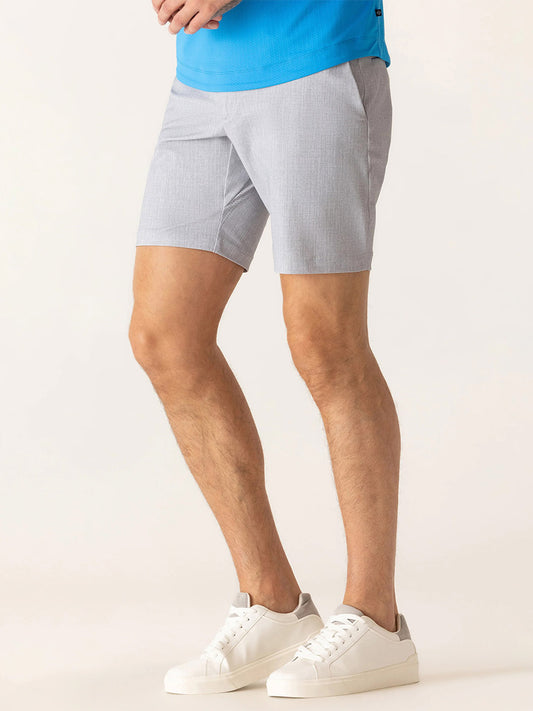 Wearing a blue Nano Nylon Warp Knit shirt, DEKE Galaxy Bermuda Nano Nylon Warp Knit shorts in Silver, and white sneakers, a person stands against a plain light background.