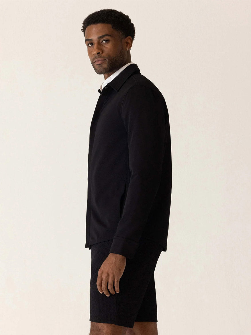 A man wearing a black DEKE Getaway Shirt Jacket in Black Twilight Twill Jersey™ over a white collared shirt.