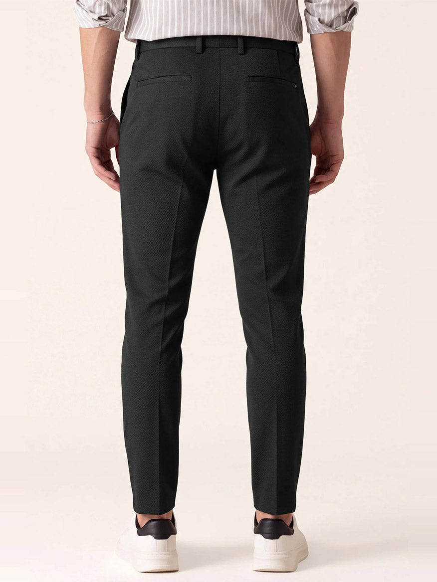 Back view of a person wearing DEKE Mobile Flat Front Pant in Black Twilight Twill Jersey™ and white sneakers.