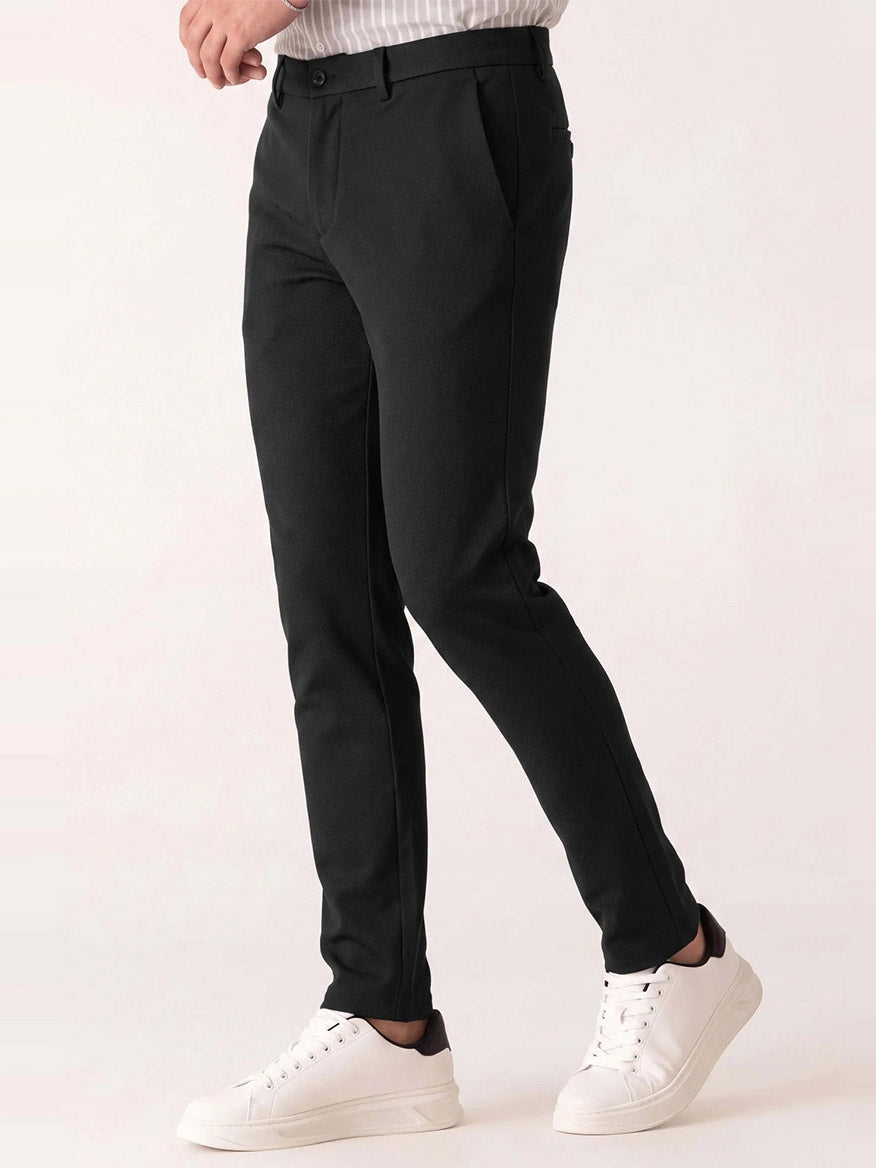 Person wearing black DEKE Mobile Flat Front Pant in Black Twilight Twill Jersey™ and white sneakers.