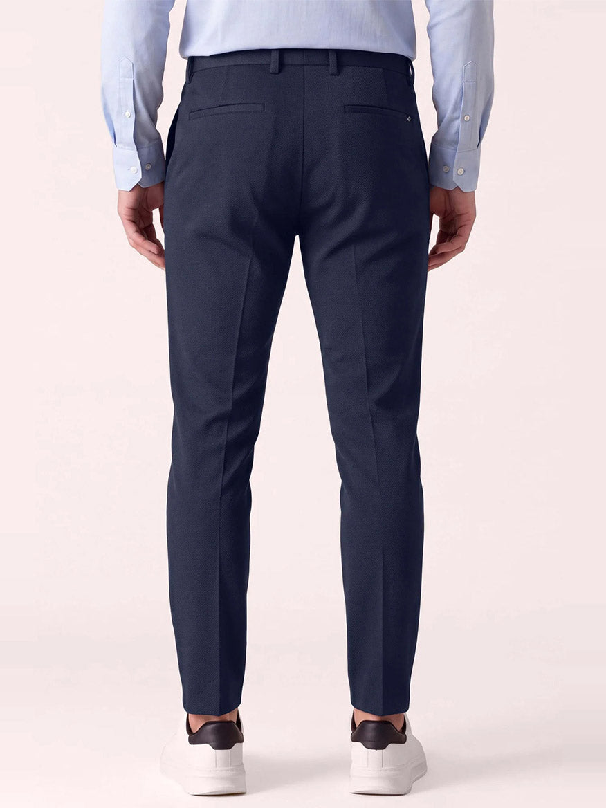 Back view of a person wearing DEKE Mobile Flat Front Pant in Midnight Twilight Twill Jersey™, a light blue button-down shirt, and white sneakers.