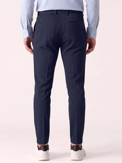 Back view of a person wearing DEKE Mobile Flat Front Pant in Midnight Twilight Twill Jersey™, a light blue button-down shirt, and white sneakers.