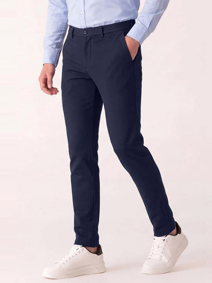 Man wearing DEKE Mobile Flat Front Pant in Midnight Twilight Twill Jersey™, a light blue button-down shirt, and white sneakers.