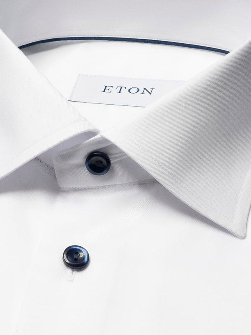 Close-up of the Eton Classic Fit Solid Signature Twill Dress Shirt in white with navy details, highlighting the collar, two dark buttons, and the Eton label inside the neckline.
