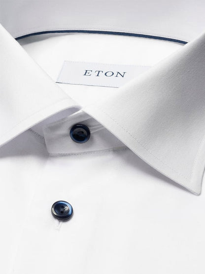 Close-up of the Eton Classic Fit Solid Signature Twill Dress Shirt in white with navy details, highlighting the collar, two dark buttons, and the Eton label inside the neckline.
