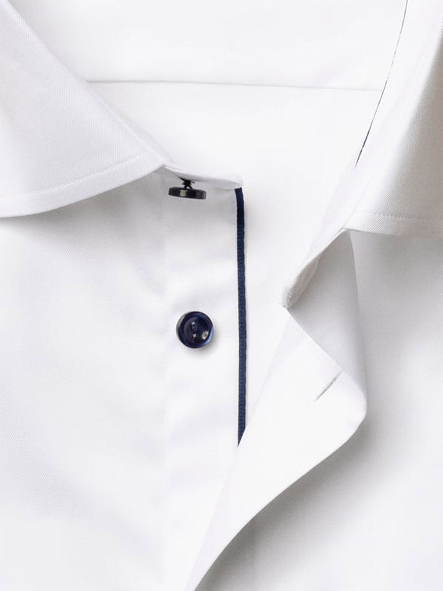Close-up of the Eton Classic Fit Solid Signature Twill Dress Shirt in white with navy details, showcasing a white fabric, navy button, and a contrasting seam along the placket.