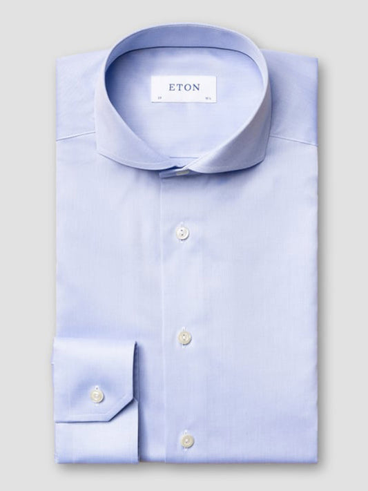 An Eton Slim Fit Sky Blue Extreme Cut Away Dress Shirt, neatly folded with white buttons, is shown against a plain light gray background.