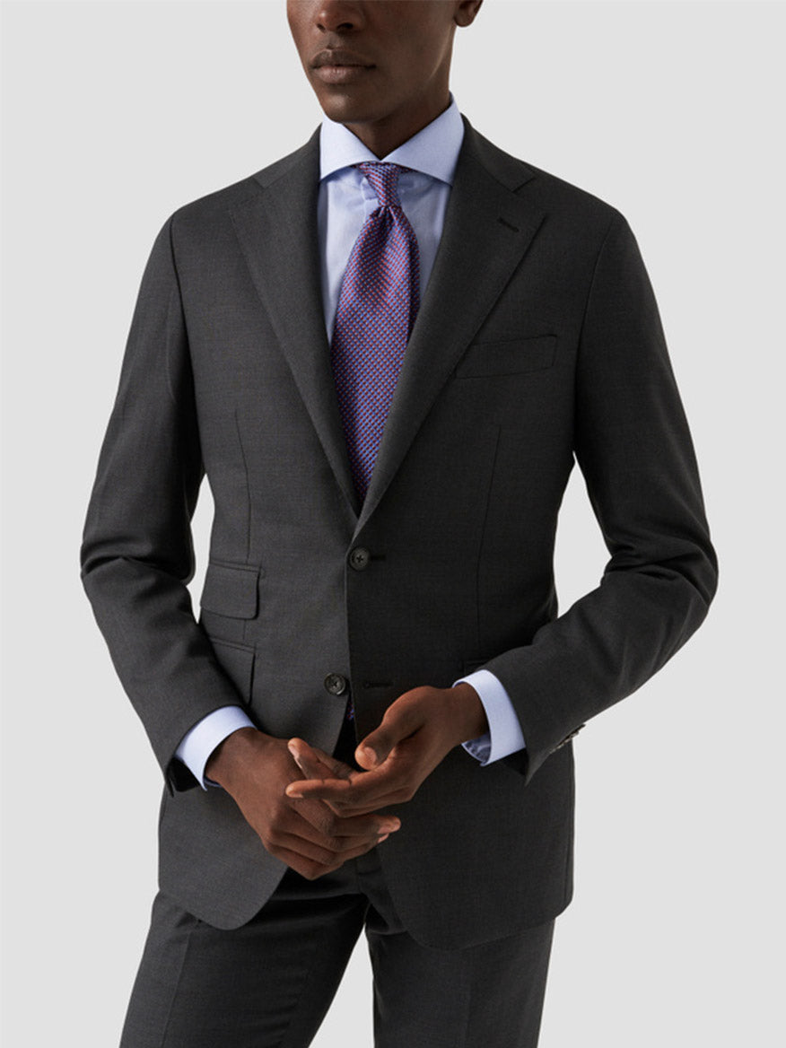 A person wearing a dark gray suit with an Eton Slim Fit Extreme Cut Away Dress Shirt in Sky Blue and a purple patterned tie, standing against a plain light background.