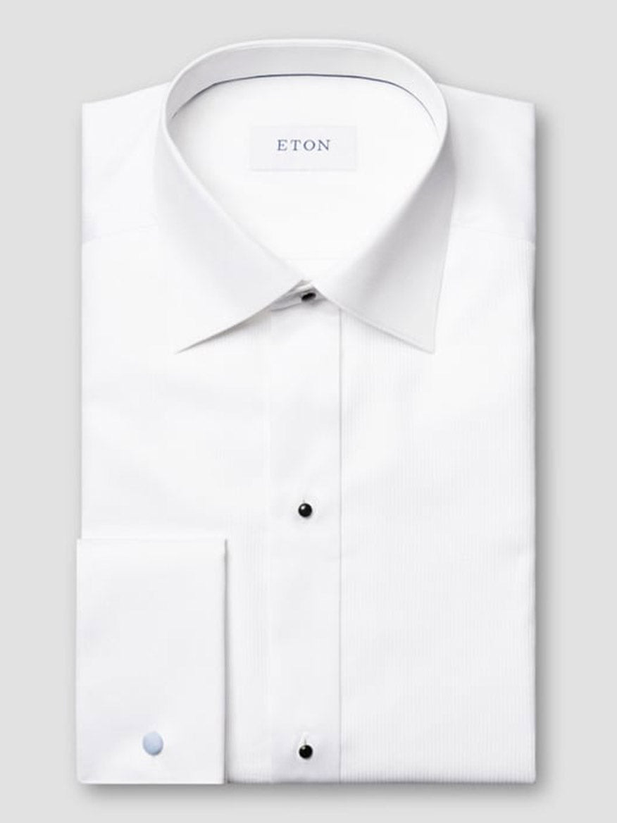 A neatly folded Eton Contemporary Fit Fine Striped Bib Evening Shirt in White with French cuffs, pointed collar, and black buttons, featuring the ETON brand label inside the collar.