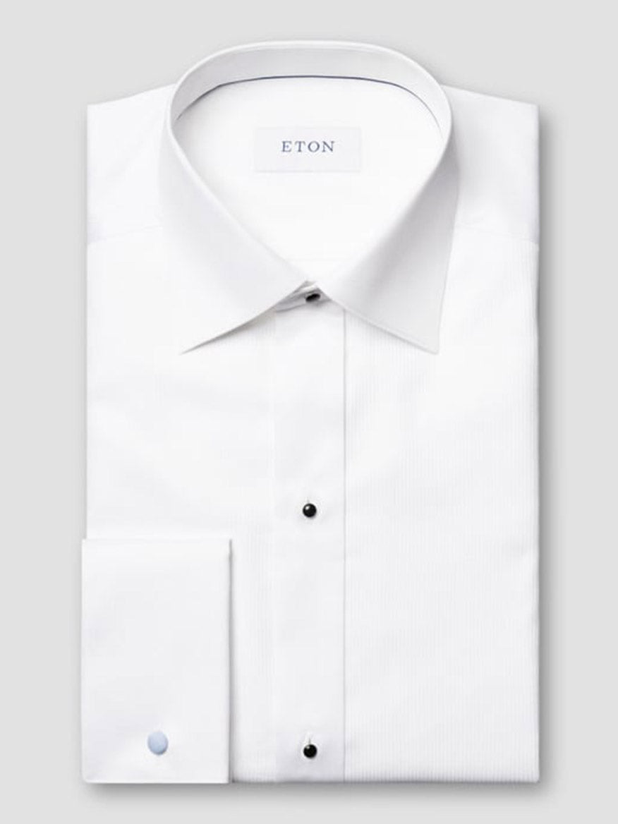 The Eton Slim Fit Fine Striped Bib Evening Shirt in White features a spread collar, French cuffs, black buttons, and a slim fit, displayed folded on a light gray background with the "ETON" label visible.