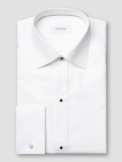 The Eton Slim Fit Fine Striped Bib Evening Shirt in White features a spread collar, French cuffs, black buttons, and a slim fit, displayed folded on a light gray background with the "ETON" label visible.