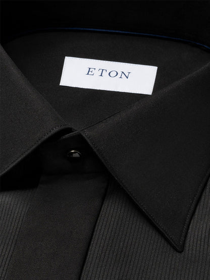 Close-up of an Eton Slim Fit Fine Striped Bib Evening Shirt in Black with a pointed collar, French cuffs, and a visible brand label on the inside.