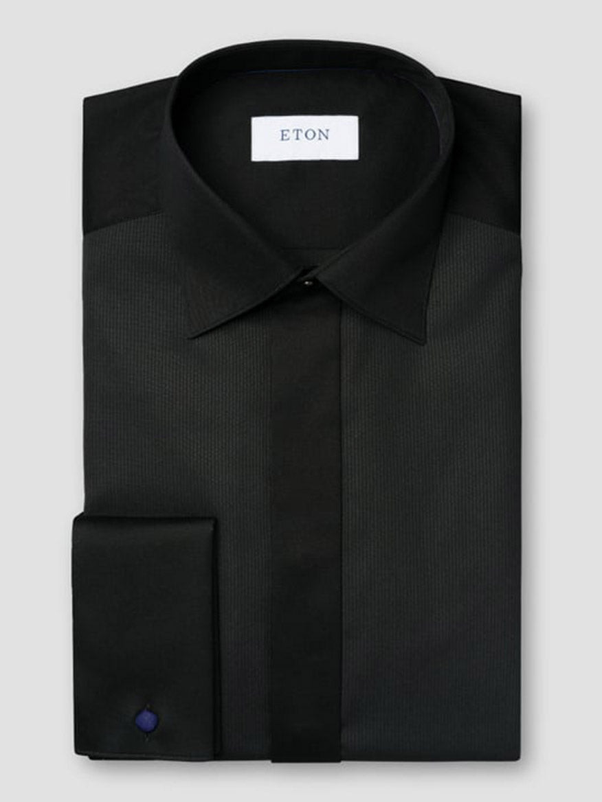 A neatly folded Eton Slim Fit Fine Striped Bib Evening Shirt in black with French cuffs, featuring a stiff collar and the brand label inside.